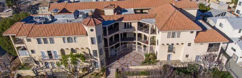 A large house with a red tile roof and a circular driveway.